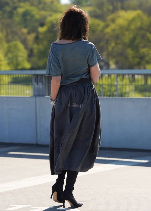 Grafitowa spódnica damska o kroju bombki z kieszeniami i dekoracyjnymi przeszyciami, pokazana w stylizacji z zielonym swetrem i czarnymi botkami na obcasie.