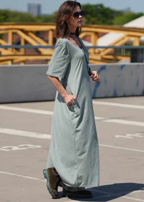 Kombinezon damski oversize w kolorze khaki z szerokimi nogawkami i wycięciem na plecach, stylizacja miejska z paskiem i biżuterią.