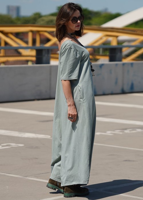 Kombinezon damski oversize w kolorze khaki z szerokimi nogawkami i wycięciem na plecach, stylizacja miejska z paskiem i biżuterią.