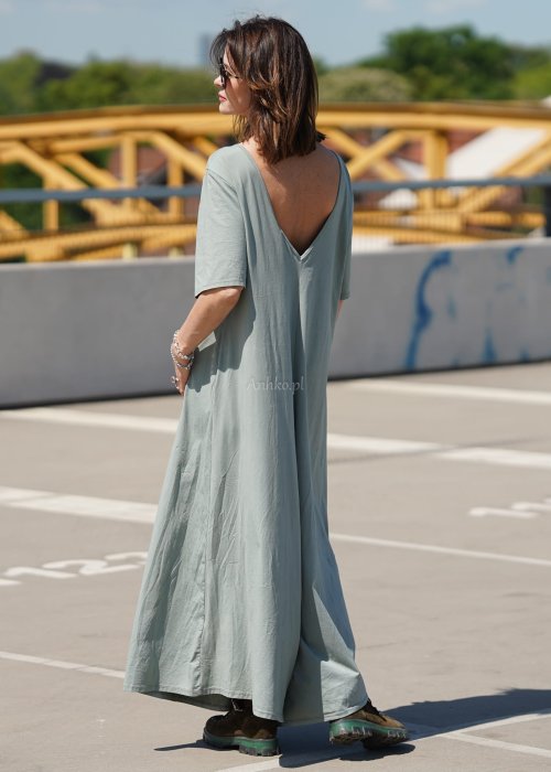 Kombinezon damski oversize w kolorze khaki z szerokimi nogawkami i wycięciem na plecach, stylizacja miejska z paskiem i biżuterią.