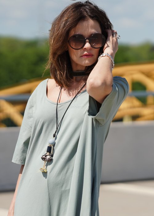 Kombinezon damski oversize w kolorze khaki z szerokimi nogawkami i wycięciem na plecach, stylizacja miejska z paskiem i biżuterią.