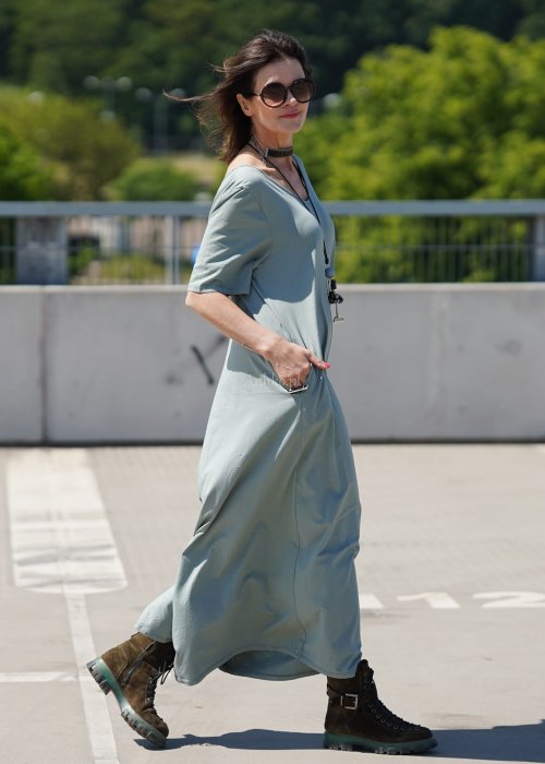 Kombinezon damski oversize w kolorze khaki z szerokimi nogawkami i wycięciem na plecach, stylizacja miejska z paskiem i biżuterią.