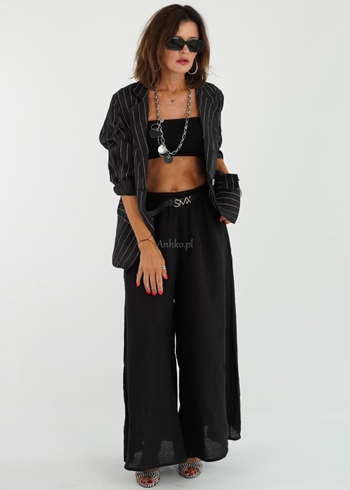 Czarne lniane spodnie damskie z bardzo szeroką nogawką i gumą w pasie, model z kieszeniami po bokach w swobodnej stylizacji.