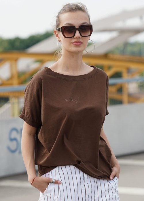 Brązowa bluzka damska oversize z krótkim rękawem i szerokim dekoltem w codziennej stylizacji z jasnymi spodniami w paski.