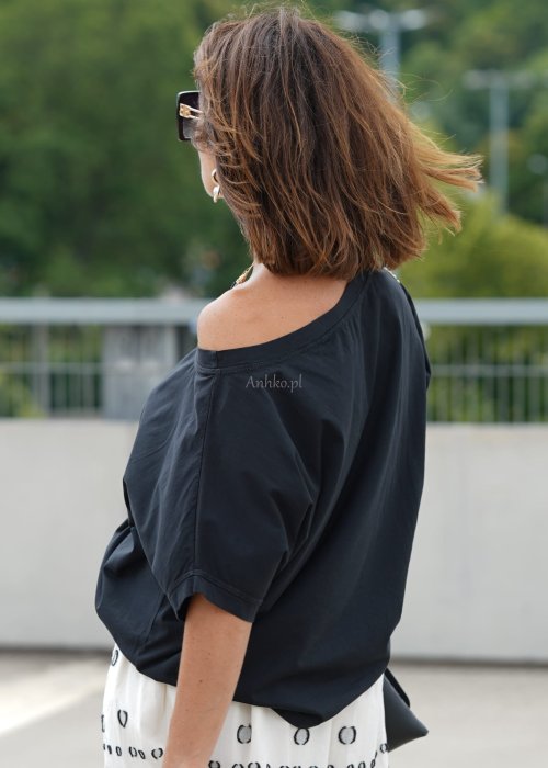 Czarna bluzka oversize z szerokim dekoltem i krótkim rękawem, stylizowana z jasną spódnicą i paskiem w eleganckim, miejskim wydaniu