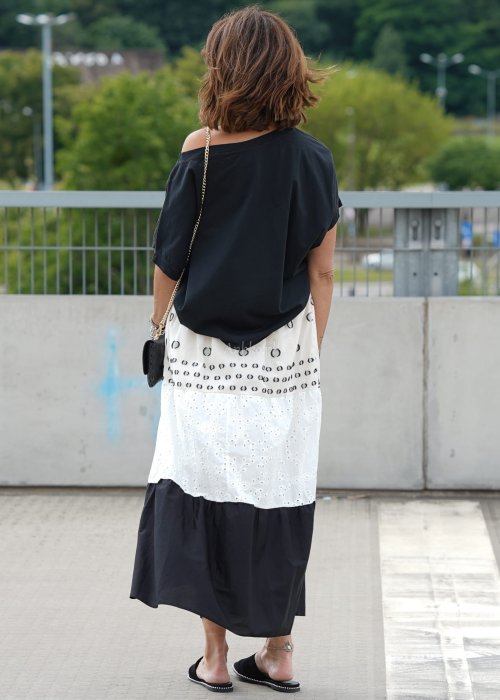 Czarna bluzka oversize z szerokim dekoltem i krótkim rękawem, stylizowana z jasną spódnicą i paskiem w eleganckim, miejskim wydaniu