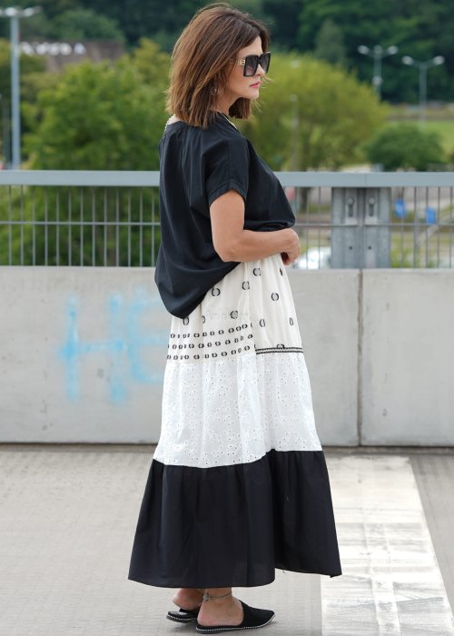 Czarna bluzka oversize z szerokim dekoltem i krótkim rękawem, stylizowana z jasną spódnicą i paskiem w eleganckim, miejskim wydaniu