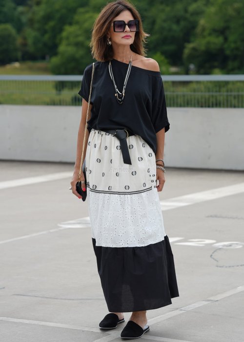 Czarna bluzka oversize z szerokim dekoltem i krótkim rękawem, stylizowana z jasną spódnicą i paskiem w eleganckim, miejskim wydaniu