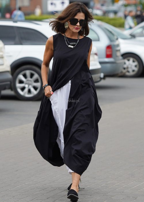 Czarna sukienka oversize o asymetrycznym kroju z zakładkami i rozcięciem, w stylizacji z płaskimi butami i dodatkami w miejskim, nowoczesnym wydaniu.