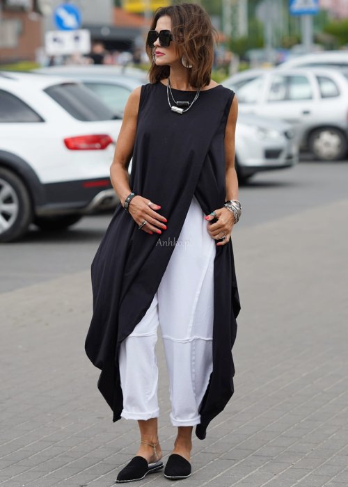 Czarna sukienka oversize o asymetrycznym kroju z zakładkami i rozcięciem, w stylizacji z płaskimi butami i dodatkami w miejskim, nowoczesnym wydaniu.