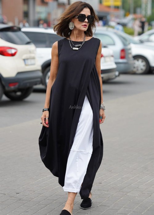 Czarna sukienka oversize o asymetrycznym kroju z zakładkami i rozcięciem, w stylizacji z płaskimi butami i dodatkami w miejskim, nowoczesnym wydaniu.