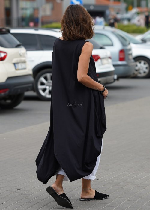 Czarna sukienka oversize o asymetrycznym kroju z zakładkami i rozcięciem, w stylizacji z płaskimi butami i dodatkami w miejskim, nowoczesnym wydaniu.