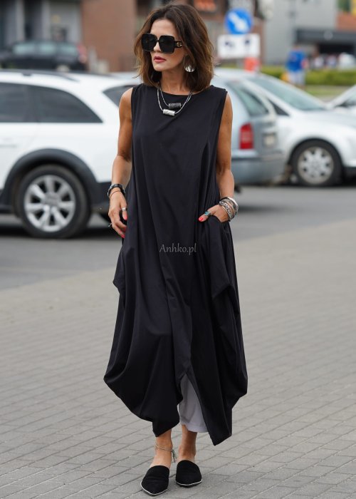 Czarna sukienka oversize o asymetrycznym kroju z zakładkami i rozcięciem, w stylizacji z płaskimi butami i dodatkami w miejskim, nowoczesnym wydaniu.