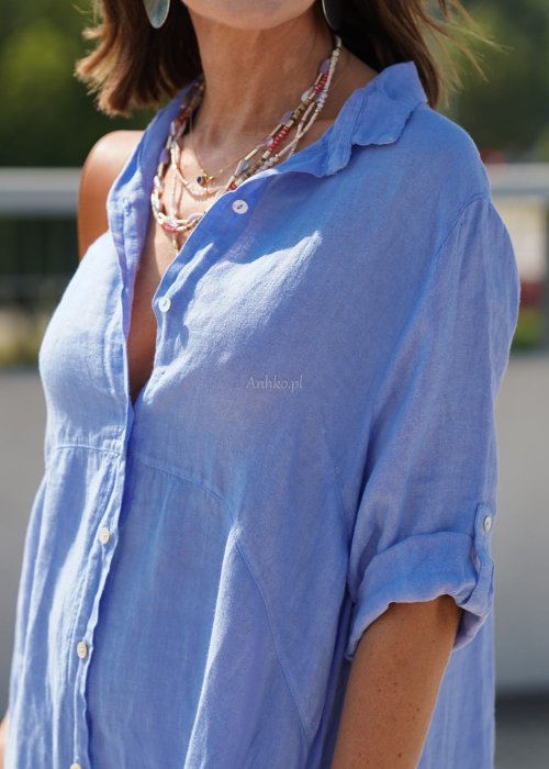 Niebieska lniana sukienka maxi w stylu szmizjerki, zapinana na guziki, o luźnym fasonie oversize, stylizowana z sandałami i torebką na ramię.