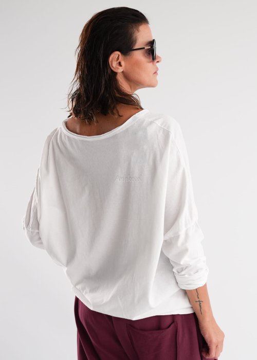Biała bluzka damska oversize z długim rękawem i dekoltem V w stylizacji z jeansami i różowym naszyjnikiem.