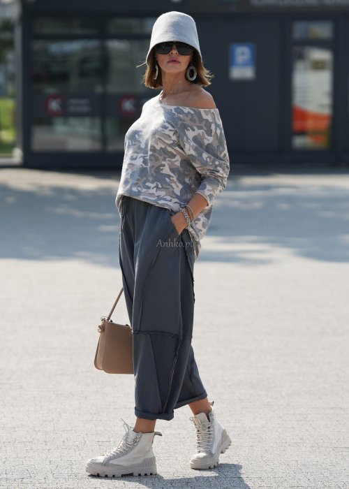 Szare spodnie damskie oversize z ozdobnymi przeszyciami i elastycznym pasem. Stylizacja z bluzką w print i jasnymi botkami w miejskim stylu.