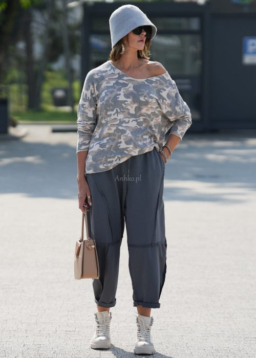 Szare spodnie damskie oversize z ozdobnymi przeszyciami i elastycznym pasem. Stylizacja z bluzką w print i jasnymi botkami w miejskim stylu.