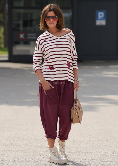 Bordowe spodnie damskie oversize z dużymi kieszeniami i elastycznym pasem. Stylizacja z czarną bluzką i ciężkimi botkami w miejskim stylu.