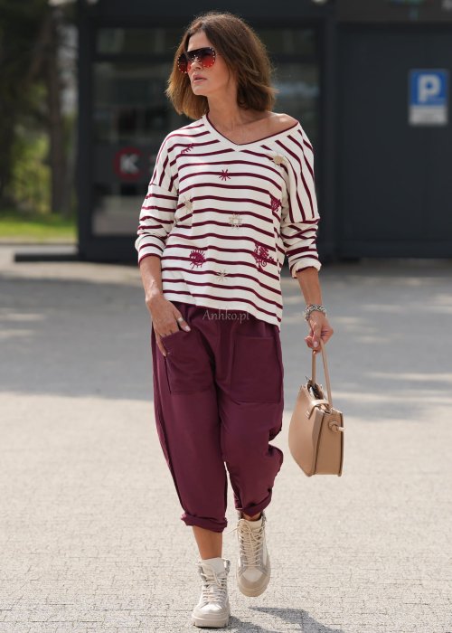 Bordowe spodnie damskie oversize z dużymi kieszeniami i elastycznym pasem. Stylizacja z czarną bluzką i ciężkimi botkami w miejskim stylu.
