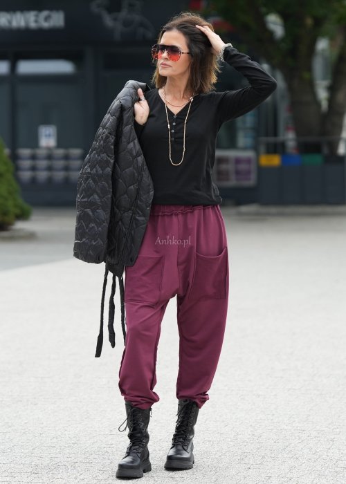 Bordowe spodnie damskie oversize z dużymi kieszeniami i elastycznym pasem. Stylizacja z czarną bluzką i ciężkimi botkami w miejskim stylu.