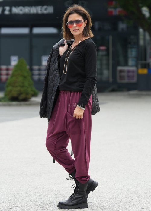 Bordowe spodnie damskie oversize z dużymi kieszeniami i elastycznym pasem. Stylizacja z czarną bluzką i ciężkimi botkami w miejskim stylu.