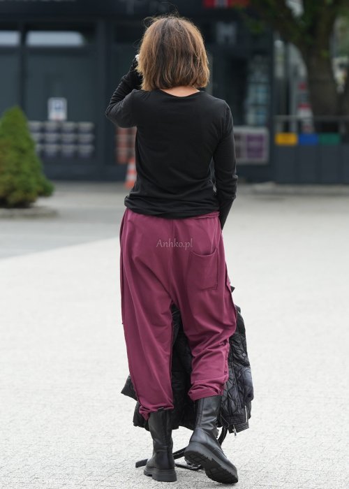 Bordowe spodnie damskie oversize z dużymi kieszeniami i elastycznym pasem. Stylizacja z czarną bluzką i ciężkimi botkami w miejskim stylu.