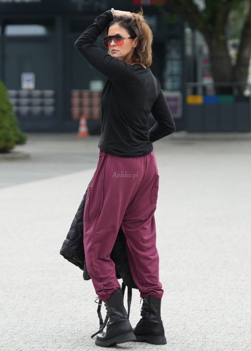 Bordowe spodnie damskie oversize z dużymi kieszeniami i elastycznym pasem. Stylizacja z czarną bluzką i ciężkimi botkami w miejskim stylu.