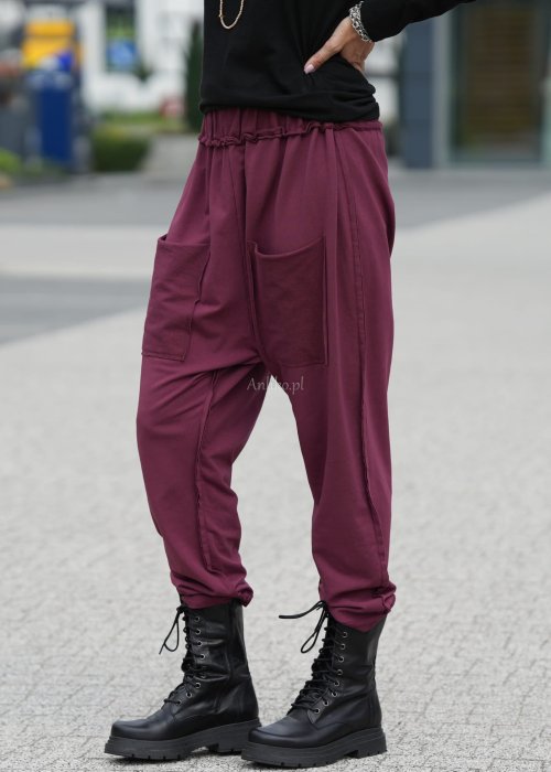 Bordowe spodnie damskie oversize z dużymi kieszeniami i elastycznym pasem. Stylizacja z czarną bluzką i ciężkimi botkami w miejskim stylu.