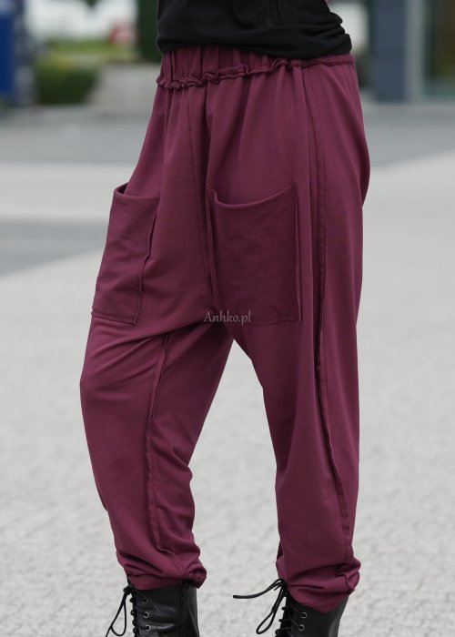 Bordowe spodnie damskie oversize z dużymi kieszeniami i elastycznym pasem. Stylizacja z czarną bluzką i ciężkimi botkami w miejskim stylu.