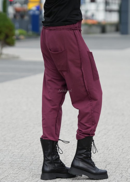 Bordowe spodnie damskie oversize z dużymi kieszeniami i elastycznym pasem. Stylizacja z czarną bluzką i ciężkimi botkami w miejskim stylu.