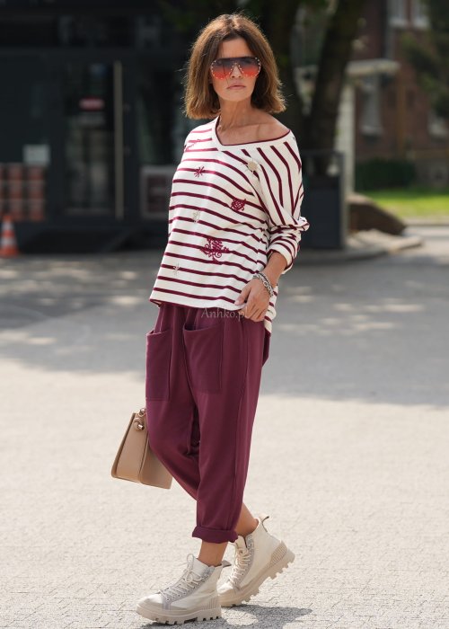 Bordowe spodnie damskie oversize z dużymi kieszeniami i elastycznym pasem. Stylizacja z czarną bluzką i ciężkimi botkami w miejskim stylu.