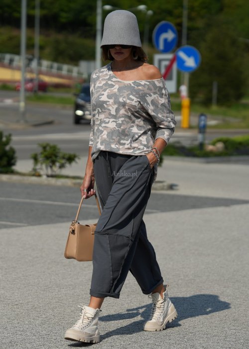 Szare spodnie damskie oversize z ozdobnymi przeszyciami i elastycznym pasem. Stylizacja z bluzką w print i jasnymi botkami w miejskim stylu.