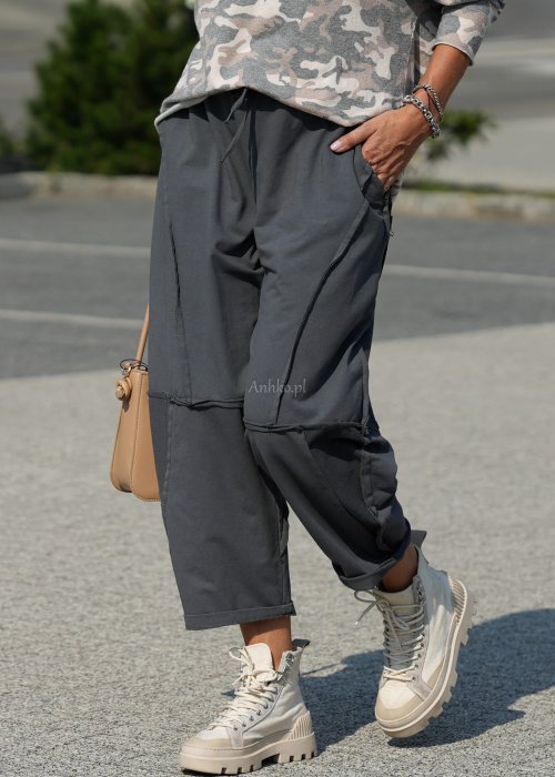 Szare spodnie damskie oversize z ozdobnymi przeszyciami i elastycznym pasem. Stylizacja z bluzką w print i jasnymi botkami w miejskim stylu.