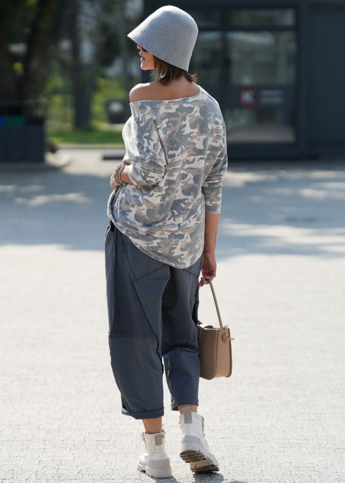 Szare spodnie damskie oversize z ozdobnymi przeszyciami i elastycznym pasem. Stylizacja z bluzką w print i jasnymi botkami w miejskim stylu.