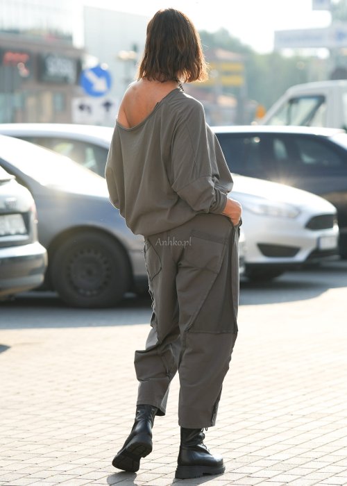 Bluzka damska oversize w kolorze taupe z szerokim dekoltem odsłaniającym ramię, wykonana z bawełny. Stylizacja casual z dodatkami i spodniami.