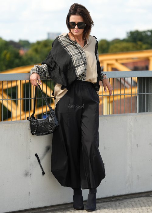Czarne spodnie damskie z szeroką nogawką i efektem bombki, z elastycznym pasem. Stylizacja z botkami na obcasie w nowoczesnym, miejskim stylu.