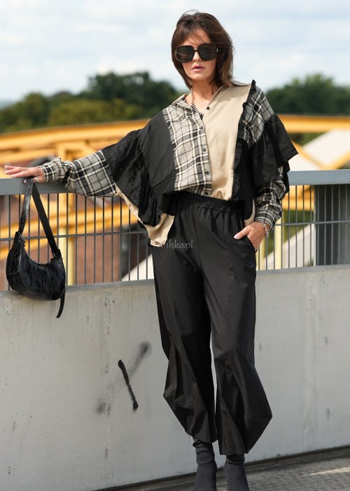 Czarne spodnie damskie z szeroką nogawką i efektem bombki, z elastycznym pasem. Stylizacja z botkami na obcasie w nowoczesnym, miejskim stylu.