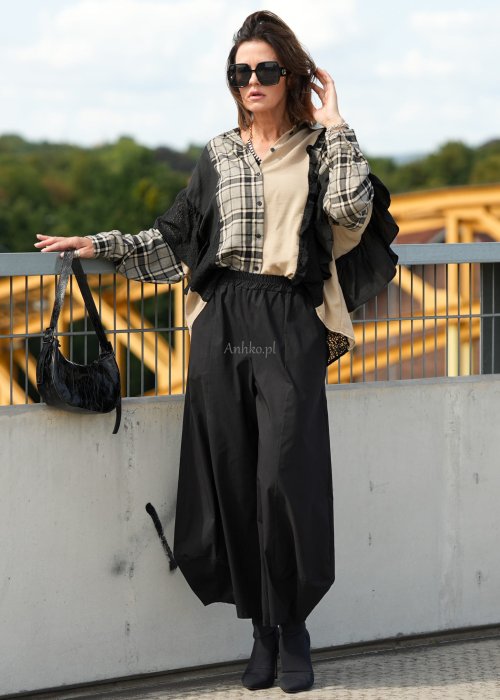 Czarne spodnie damskie z szeroką nogawką i efektem bombki, z elastycznym pasem. Stylizacja z botkami na obcasie w nowoczesnym, miejskim stylu.
