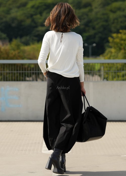 Czarne spodnie damskie z szeroką nogawką i efektem bombki, z elastycznym pasem. Stylizacja z botkami na obcasie w nowoczesnym, miejskim stylu.