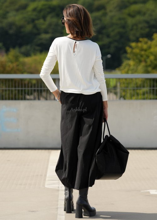 Czarne spodnie damskie z szeroką nogawką i efektem bombki, z elastycznym pasem. Stylizacja z botkami na obcasie w nowoczesnym, miejskim stylu.