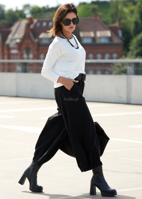 Czarne spodnie damskie z szeroką nogawką i efektem bombki, z elastycznym pasem. Stylizacja z botkami na obcasie w nowoczesnym, miejskim stylu.