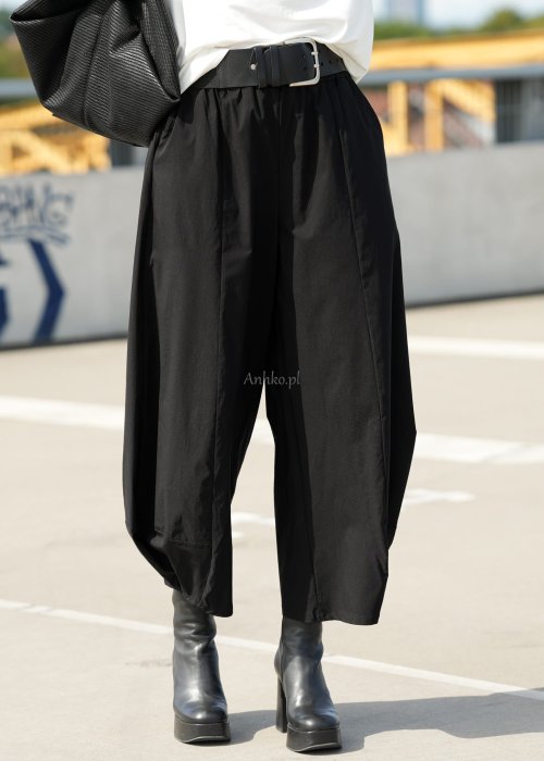 Czarne spodnie damskie z szeroką nogawką i efektem bombki, z elastycznym pasem. Stylizacja z botkami na obcasie w nowoczesnym, miejskim stylu.