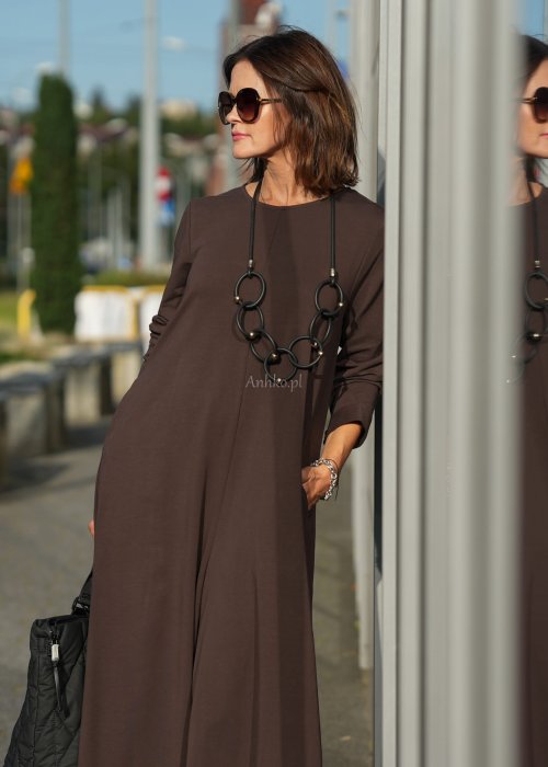 Brązowy kombinezon damski z długim rękawem i bardzo szeroką nogawką, luźny fason z półokrągłym dekoltem w miejskiej stylizacji z botkami.