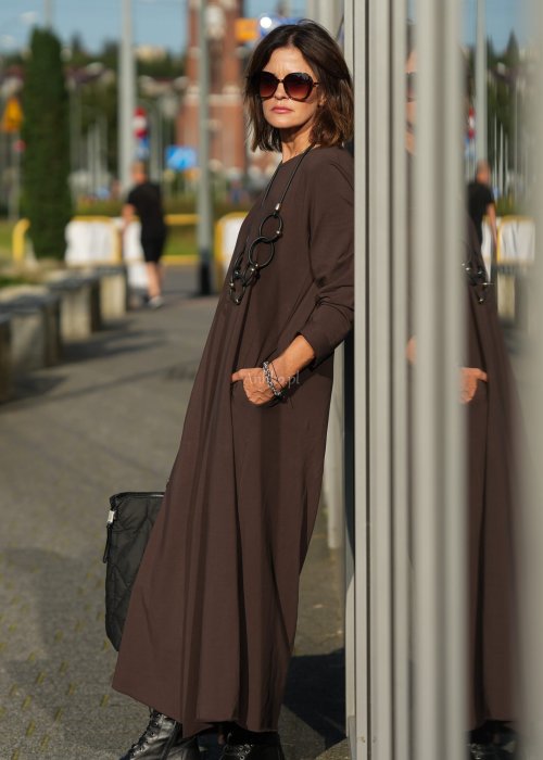 Brązowy kombinezon damski z długim rękawem i bardzo szeroką nogawką, luźny fason z półokrągłym dekoltem w miejskiej stylizacji z botkami.