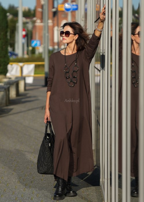 Brązowy kombinezon damski z długim rękawem i bardzo szeroką nogawką, luźny fason z półokrągłym dekoltem w miejskiej stylizacji z botkami.