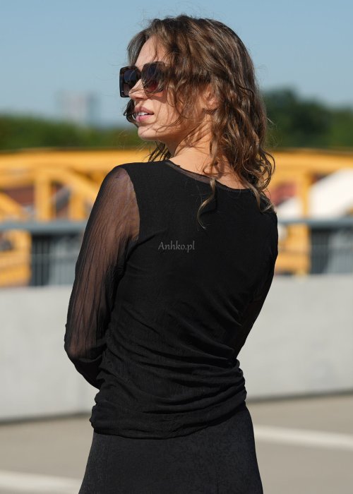 Czarna bluzka damska z transparentnymi rękawami i dekoltem łódka, elegancka stylizacja miejska z okularami przeciwsłonecznymi.