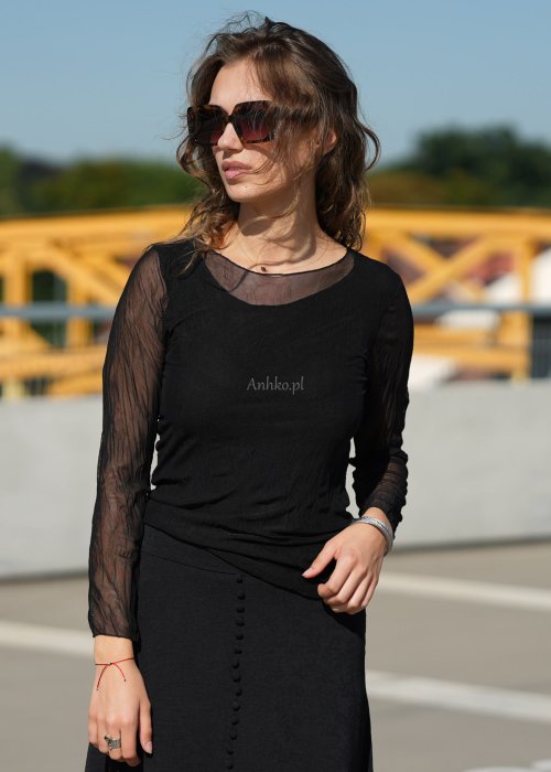 Czarna bluzka damska z transparentnymi rękawami i dekoltem łódka, elegancka stylizacja miejska z okularami przeciwsłonecznymi.