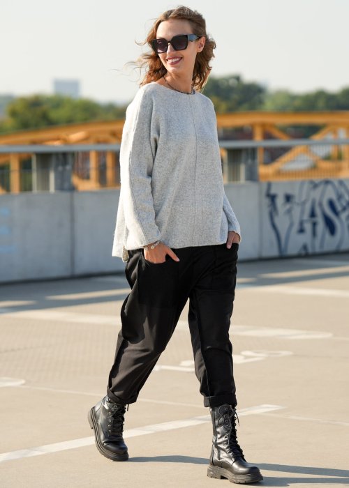 Czarne spodnie damskie o luźnym kroju z dużymi naszywanymi kieszeniami, zestawione z szarym swetrem i czarnymi botkami w miejskiej stylizacji.