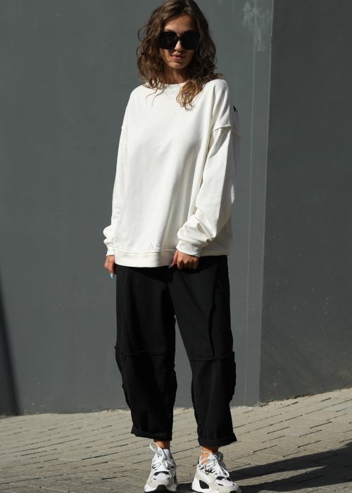 Czarne spodnie dresowe damskie o luźnym kroju baggy z ozdobnymi przeszyciami i gumką w pasie, stylizowane ze sneakersami w miejskim looku.