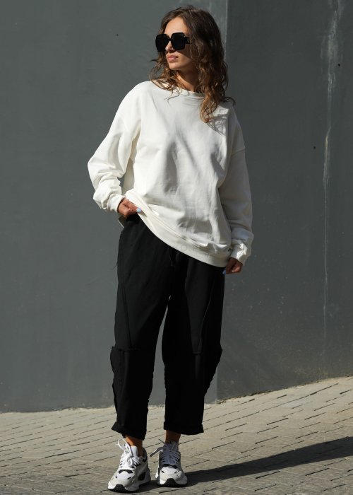Czarne spodnie dresowe damskie o luźnym kroju baggy z ozdobnymi przeszyciami i gumką w pasie, stylizowane ze sneakersami w miejskim looku.